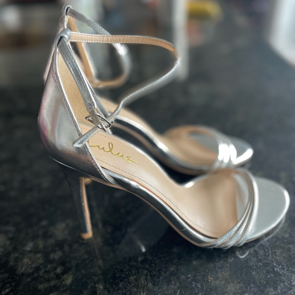 Never been worn, silver strappy high heels. 8.5